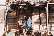 Yoff, Senegal - December 6, 2017: Portrait of man sitting and resting on bench at home in village — стоковое фото