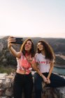 Retrato de duas mulheres tomando selfie sobre paisagem de montanha de tirar o fôlego — Fotografia de Stock