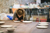 Flexion femme créer des plaques d'argile dans l'atelier — Photo de stock