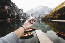 Crop hand holding compass on background of mountains and lake. — Stock Photo