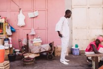 Goree, Senegal- December 6, 2017:African man in white clothes speaking to woman while standing near sleeping man. — Stock Photo
