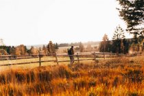 Viaggiatore posa vicino alla recinzione rurale a campo di campagna autunno — Foto stock