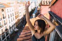 Mädchen posiert mit erhobenen Armen auf Balkon — Stockfoto