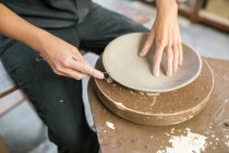 Crop potter mains façonnant bord de plaque d'argile avec instrument — Photo de stock