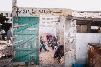 Goree, Sénégal- 6 décembre 2017 : Un groupe d'Africains assis dans un abri à moitié détruit dans la rue de la ville pauvre . — Photo de stock