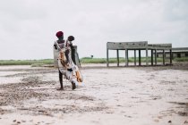 Yoff, Senegal- 6 de diciembre de 2017: Vista trasera de la mujer caminando y llevando al niño en las manos . - foto de stock