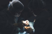 Концентрированные хирурги, обеспечивающие операцию при ярком свете лампы . — стоковое фото