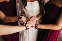 Mid section of bridesmaids holding hands together before wedding ceremony. — Stock Photo