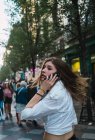 Femme brune décontractée marchant dans la rue et parlant au téléphone — Photo de stock