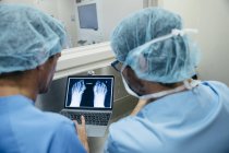 Вид ззаду на двох чоловіків у медичній формі дивитися фото рентгенівського знімка на ноутбуці — стокове фото