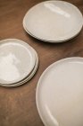 Vue rapprochée des assiettes artisanales blanches brillantes sur la table — Photo de stock
