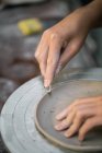 Coltivare mani vasaio femminile intaglio bordo piatto di argilla con strumento — Foto stock