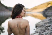 Visão traseira da menina morena topless olhando sobre o ombro na parte de trás — Fotografia de Stock
