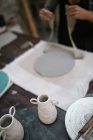 Высокий угол обзора рабочего процесса ремесленника на столе в мастерской керамики — стоковое фото