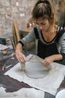 Donna bionda che lavora con attenzione con argilla sul desktop — Foto stock