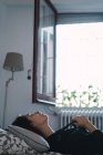 Вид сбоку на брюнетку, позирующую в постели дома — стоковое фото
