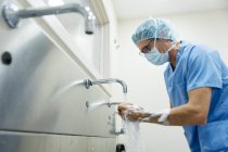 Vista lateral do cirurgião em mãos lavadas uniformes antes da operação — Fotografia de Stock
