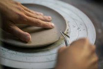 Cultiver les mains d'artisan sculptant bord plat d'argile avec instrument — Photo de stock