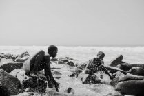 Goree, Senegal- December 6, 2017: Cheerful kids sitting on rock in splashing wavess — Stock Photo