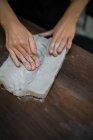 Обтинання жінки руки замішувати глини шматок на дерев'яні таблиці — стокове фото