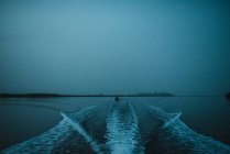 Boat trails on river calm water in dark night time. — Stock Photo