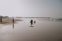 Yoff, Sénégal- 6 décembre 2017 : Paysage de plage avec de l'eau calme laver le sable et les enfants africains s'amuser dans l'eau . — Photo de stock