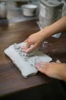 Обрізати зображення жіночих рук, розминання глини шматок на стіл — стокове фото