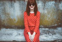 Stylish red hair woman in sunglasses on mossy stone bench — Stock Photo