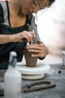 Mid section of woman making pot at table in workshop — Stock Photo