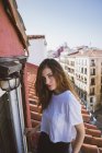 Portrait de fille brune posant sur le balcon et regardant la caméra — Photo de stock