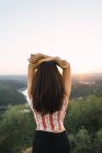 Вид спереду брюнетка дівчина позує з піднятими руками над озерною долиною сільський пейзаж — стокове фото