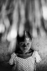 Goree, Senegal- Dezembro 6, 2017: Retrato de menina bonita em vestido posando sob telhado de palha e olhando para a câmera . — Fotografia de Stock