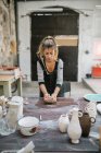 Вид спереду жіночого гончаря, що міняє глину на столі в майстерні — стокове фото