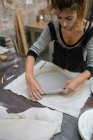 Retrato de alfarero trabajando con arcilla en el escritorio en taller - foto de stock