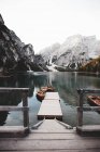 Small pier and moored boats on lake near majestic snowy mountain. — Stock Photo