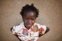 Goree, Senegal- December 6, 2017: Portrait of adorable girl in stylish bright dress looking confidently at camera. — Stock Photo