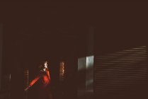Веселая девушка в ярко-красном наряде, позирующая в солнечных лучах у кирпичной стены. . — стоковое фото