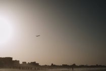 Paisaje con avión volando por encima de la pequeña ciudad en la costa del océano . - foto de stock