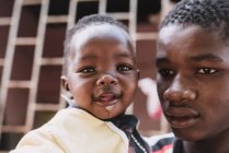 Goree, Senegal- diciembre 6, 2017: Joven negro sosteniendo a su adorable bebé en las manos . - foto de stock