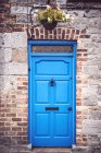 Bright blue door in brick wall of rural house. — Stock Photo