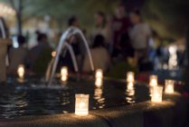 Candles lit on fountain edge in village square — Stock Photo