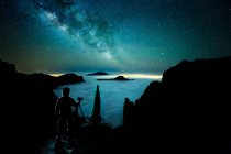Silhouette de la personne prenant des photos de paysage marin et ciel étoilé clair . — Photo de stock
