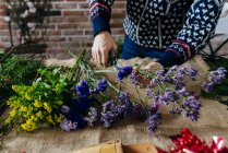 Crop florists hands cutting flowers on sacking at table — Stock Photo