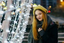 Smiling woman posing at festive illumination and looking at camera — Stock Photo