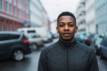 Portrait of man in warm sportive clothes looking at camera on street scene — Stock Photo