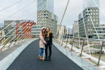 Две девушки обнимаются и позируют на мосту — стоковое фото