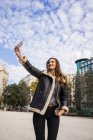 Vista de ángulo alto de la chica morena tomando selfie en la escena urbana - foto de stock