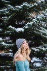 Вид збоку білява чуттєва дівчина стоїть на зимовому дереві і дивиться вгору — стокове фото