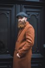 Портрет стильного бородатого мужчины, позирующего над черной дверью — стоковое фото