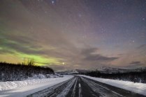 Perspectiva de la carretera de asfalto y la naturaleza cubierta de nieve en la noche de invierno . - foto de stock